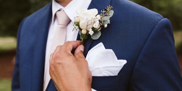 Groom adjusting his boutonniere before wedding. 