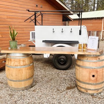 White mobile bar behind wine barrel bar used for wedding and event rentals