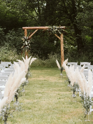 rustic wood log pole arch decorated with flowers at the end of an aisle. Wedding aisle