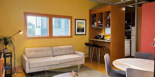 Cozy living room with yellow walls, beige sofa, and glass coffee table.
