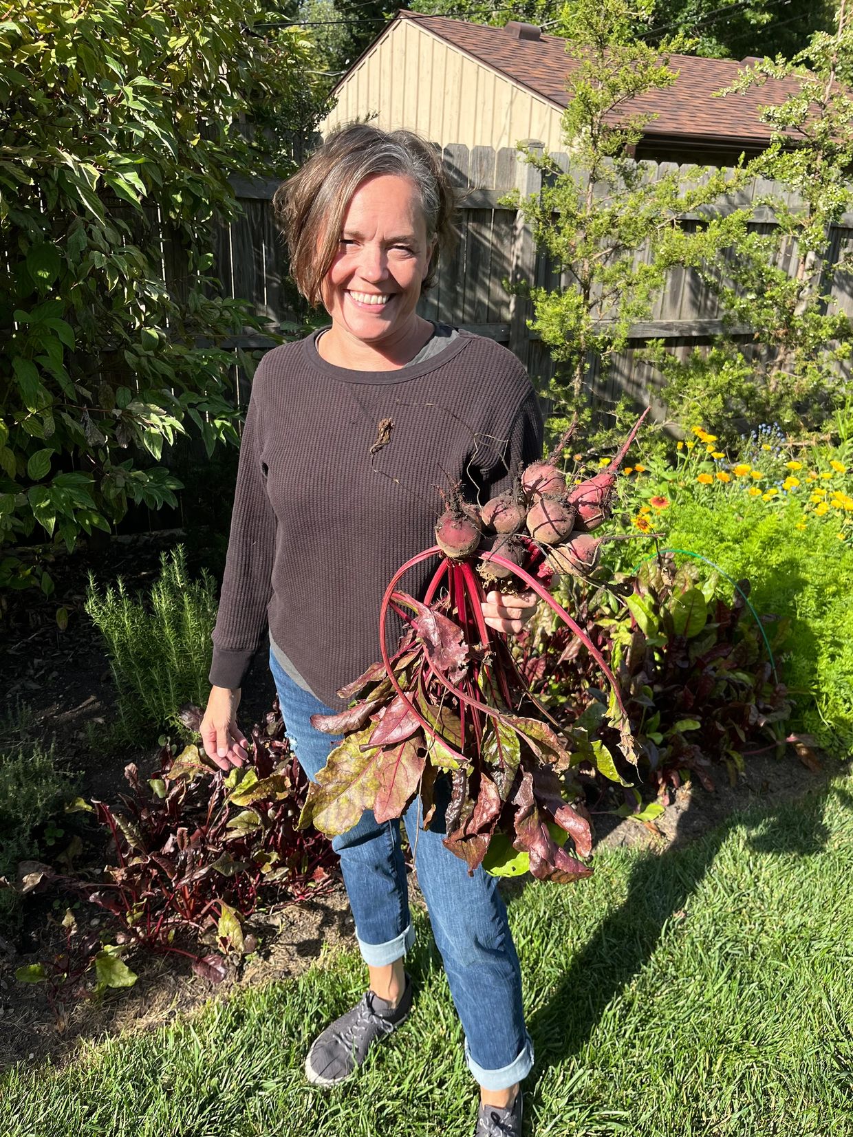 Woman holding freshly picked beetroots in a garden.