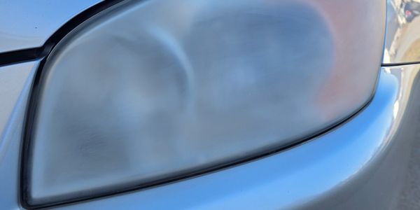 Close-up of a foggy car headlight on a silver vehicle.