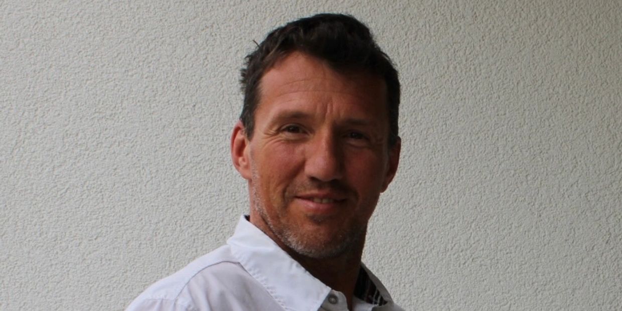 Portrait of a smiling man with a textured wall background.