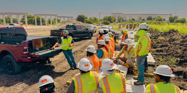 Construction workers gathered around a screen on a job site.