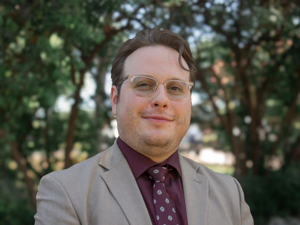 Man in a beige suit and glasses.