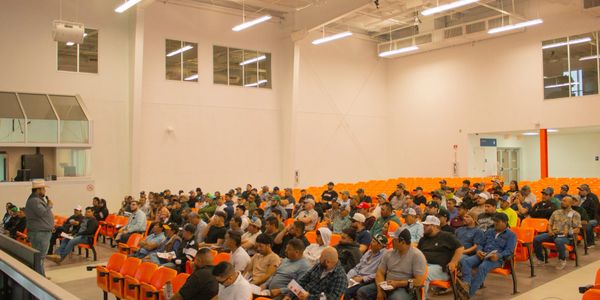 A speaker addressing a large audience in a spacious lecture hall.