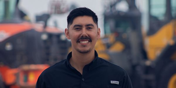 A man smiling in front of construction equipment.