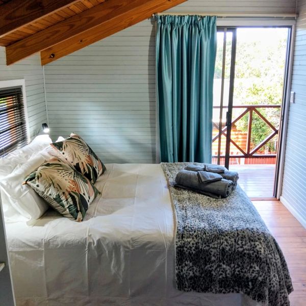 Cozy bedroom with patterned pillows and folded towels by a balcony.