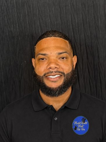 Smiling man with a beard against a black background.