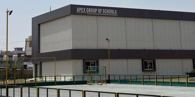 Exterior view of Apex Group of Schools building with a fenced sports area.