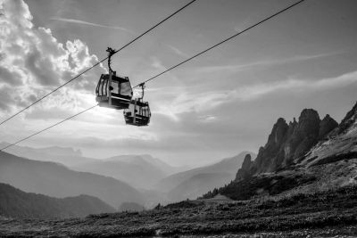 Cable cars suspended above mountainous terrain at sunset.