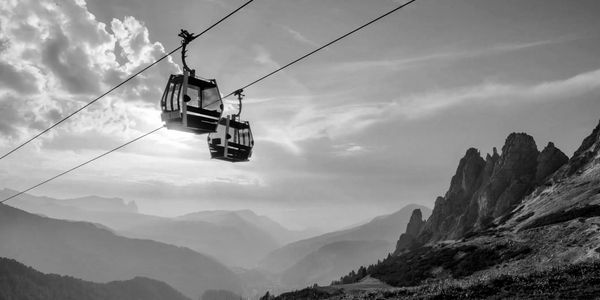 Cable cars travel over mountainous terrain at sunset.