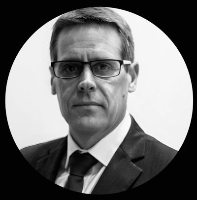 Black and white portrait of a serious man in glasses and suit.