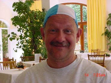 Smiling man wearing a two-tone swim cap indoors.