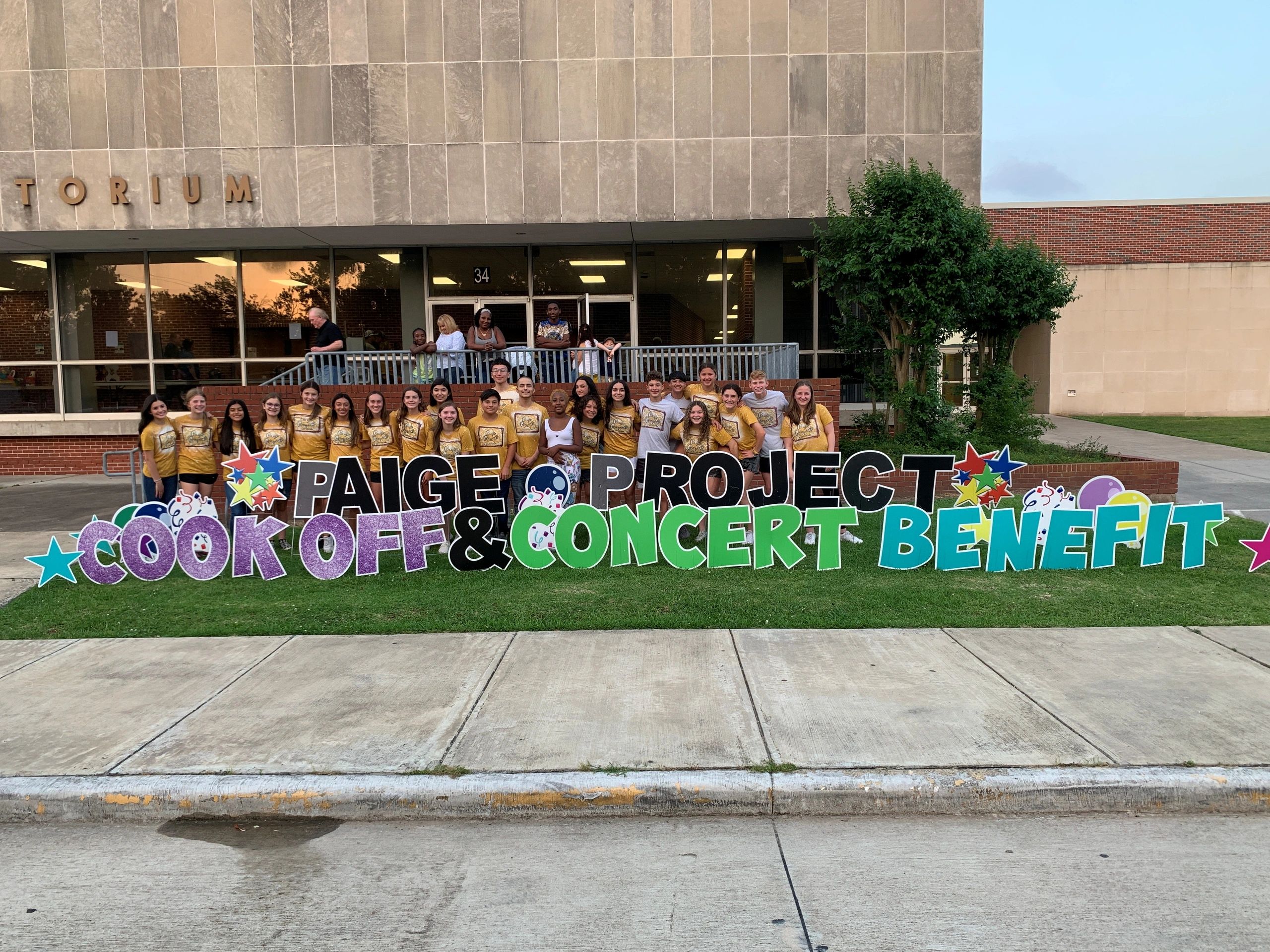 Group photo of young people in yellow shirts at a cook-off and concert benefit event.