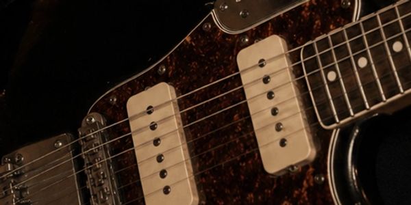 Close-up of electric guitar pickups and strings.