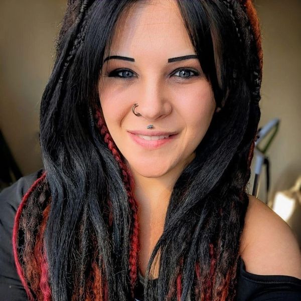 Woman with braided hair and nose piercing smiling.