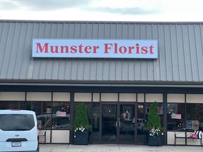Front view of Munster Florist with decorative plants and an open sign.