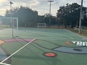 Empty outdoor sports court with soccer goals and colorful markings.