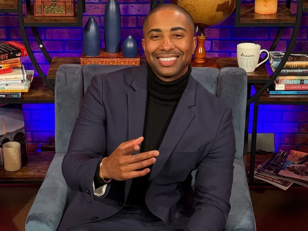 Smiling man in a suit sitting on a chair in a cozy room.