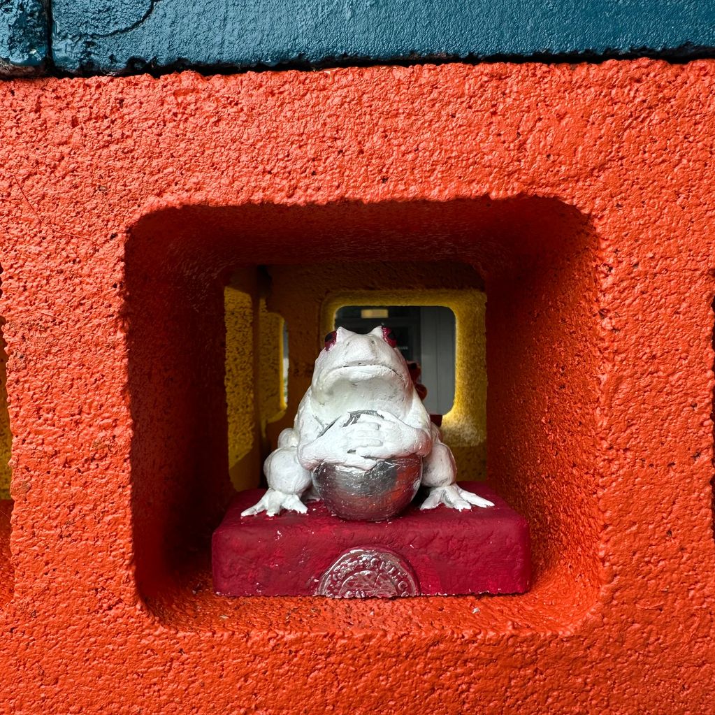 White frog statue in a colorful square recess.