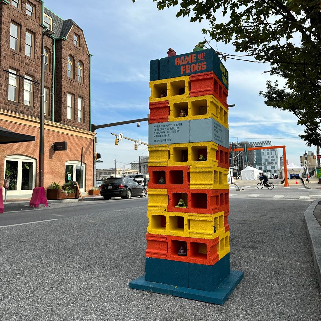 Colorful 'Game of Frogs' block tower on a city street.
