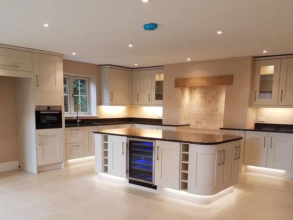 Modern kitchen with white cabinets, black countertops, and central island with wine cooler.