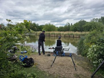 Two people fishing by a lake on a cloudy day.
