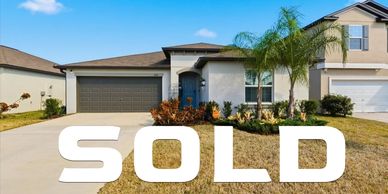 Modern single-story house with a sold sign in front.