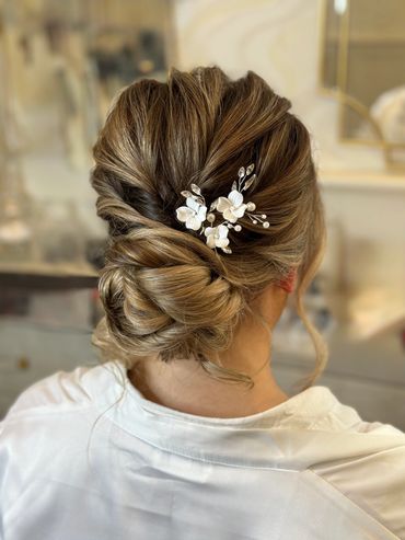 Low tousled bun with soft lines, timeless hairstyle features a low soft tousled bun bridal hairstyle