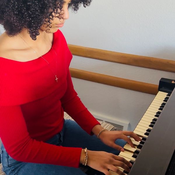 Young woman in red playing piano with concentration.