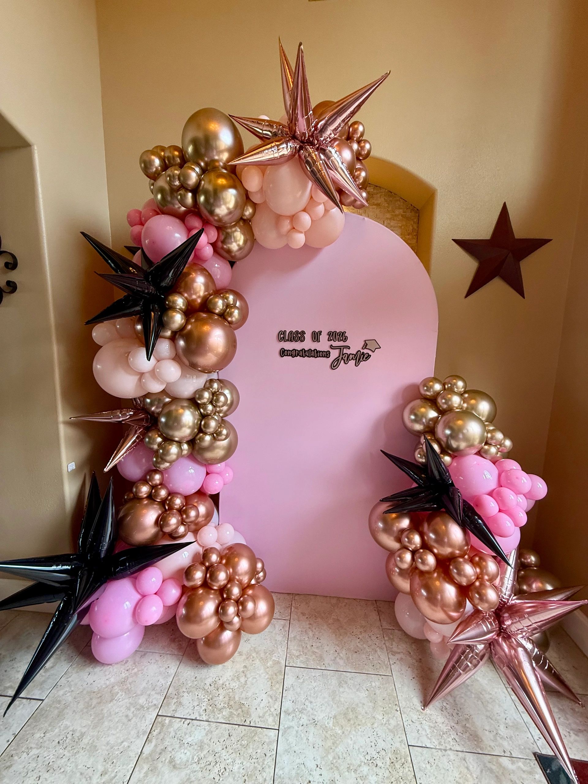 Elegant pink and gold balloon arch for a 2026 graduation celebration.