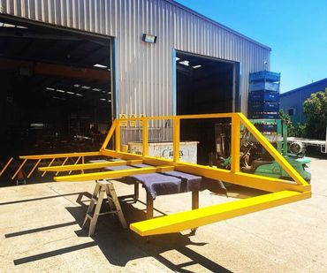 Bright yellow metal structure outside an industrial workshop on a sunny day.