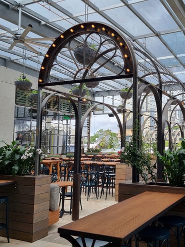 Charming indoor garden cafe with wooden furniture and hanging plants.