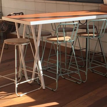 Modern wooden table with metal-framed stools in warm sunlight.