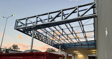 Steel framework structure under construction with a sunset sky.