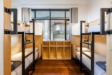 Modern dormitory room with four bunk beds and wooden flooring.