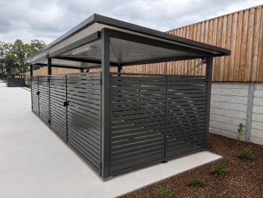 Modern black metal enclosure with slatted panels and a sloped roof.