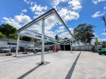 Metal framework structure on a concrete surface under a blue sky with clouds.