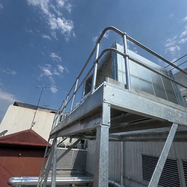 Industrial metal platform with railing under a partly cloudy sky.