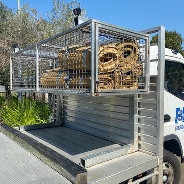 Truck carrying metal chairs secured in a cage on its flatbed.
