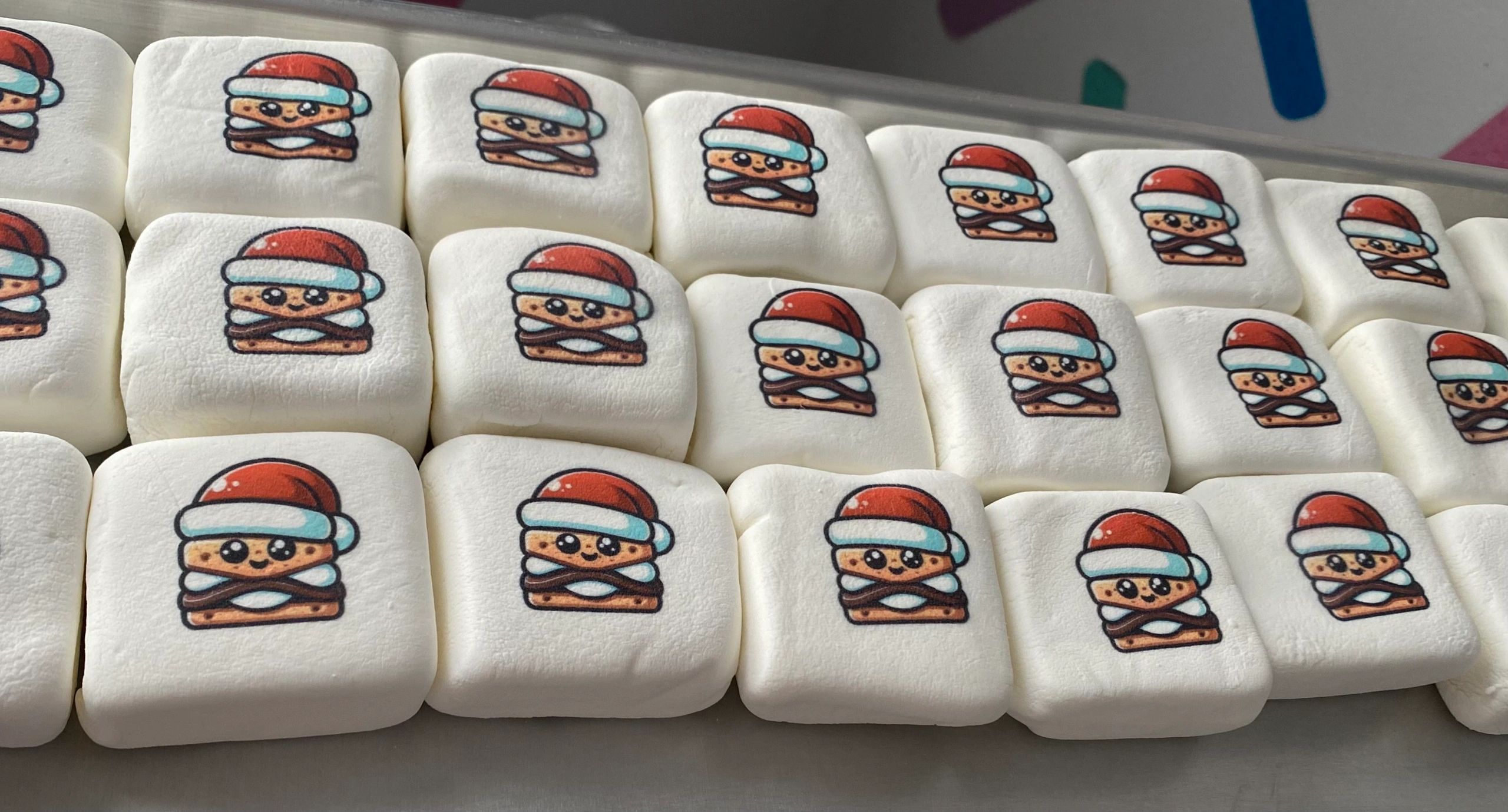 Marshmallows with printed cartoon s'mores wearing Santa hats.