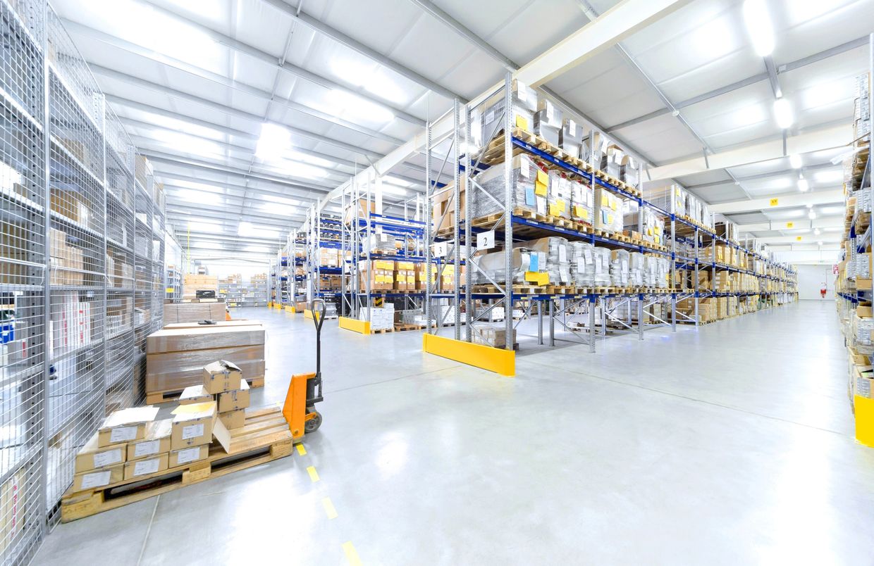 Bright warehouse with organized shelves and pallets of goods.
