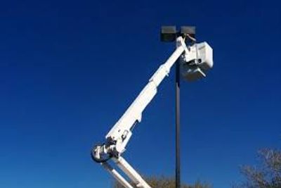 Electricians changing LED lighting on pole.