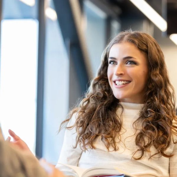 Young woman smiling and talking indoors.