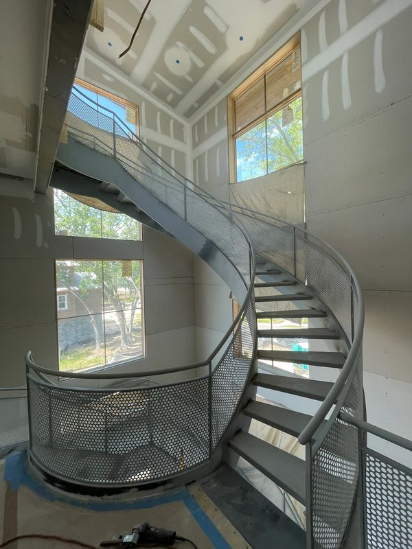 Specialty curved metal staircase with specialty railing throughout