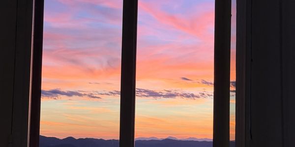 Sunset view through a window with mountains in the distance.