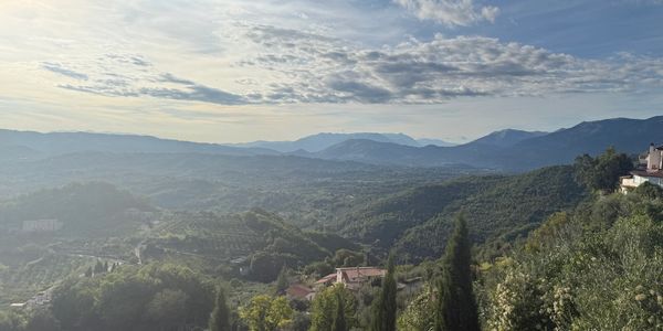 Sunlit green hills and distant mountains under a partly cloudy sky.