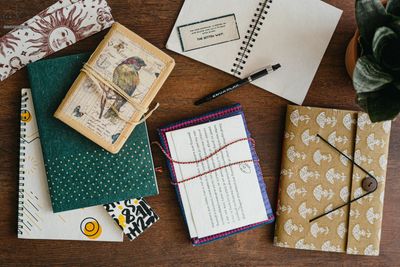 A collection of artistic notebooks and a pen on a wooden table.