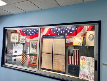 A patriotic display case with historical documents and American flags.